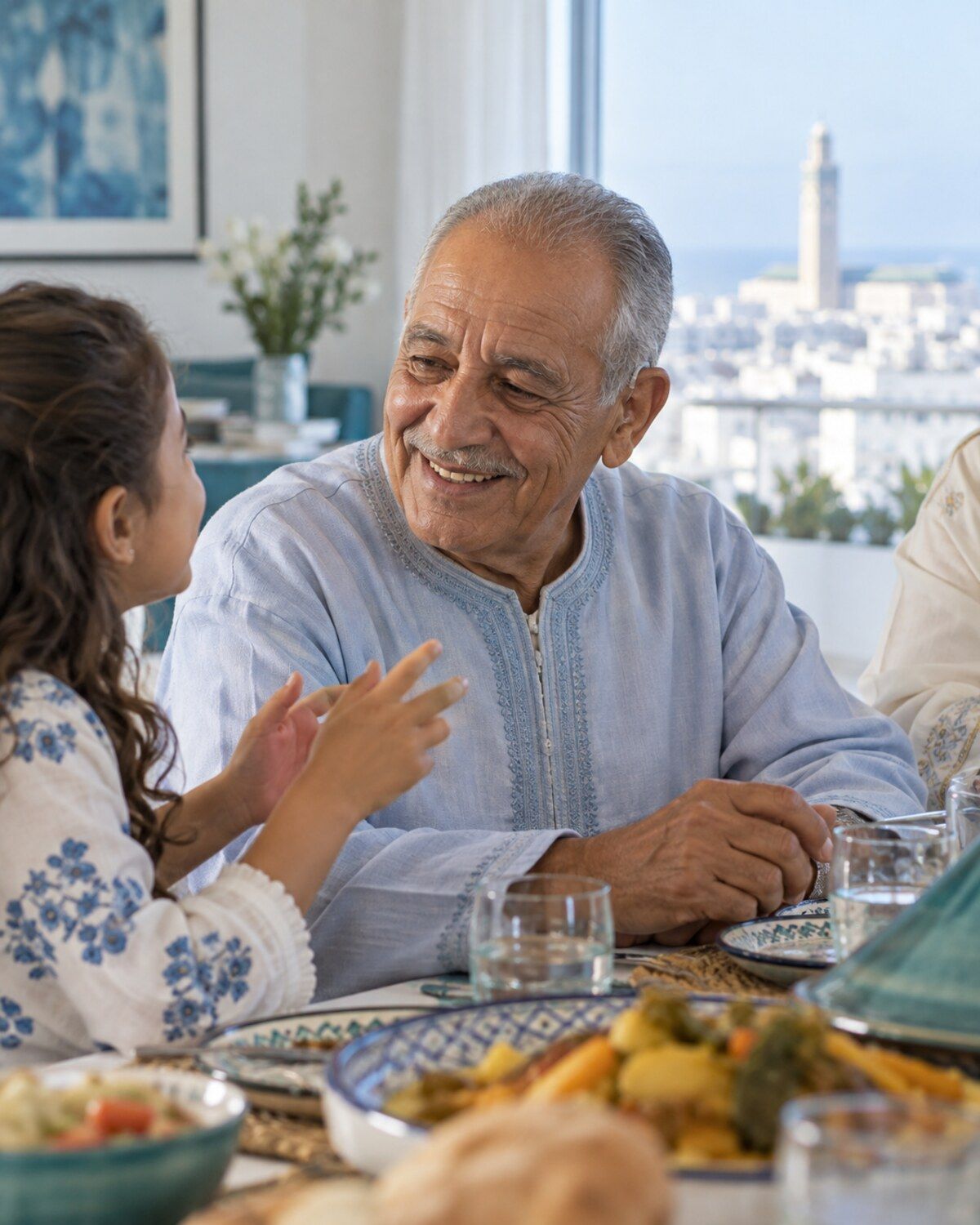 Un grand-père souriant écoute sa petite-fille pendant un repas de famille